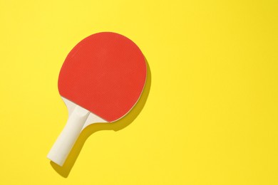 Photo of One ping pong racket on yellow background, top view. Space for text