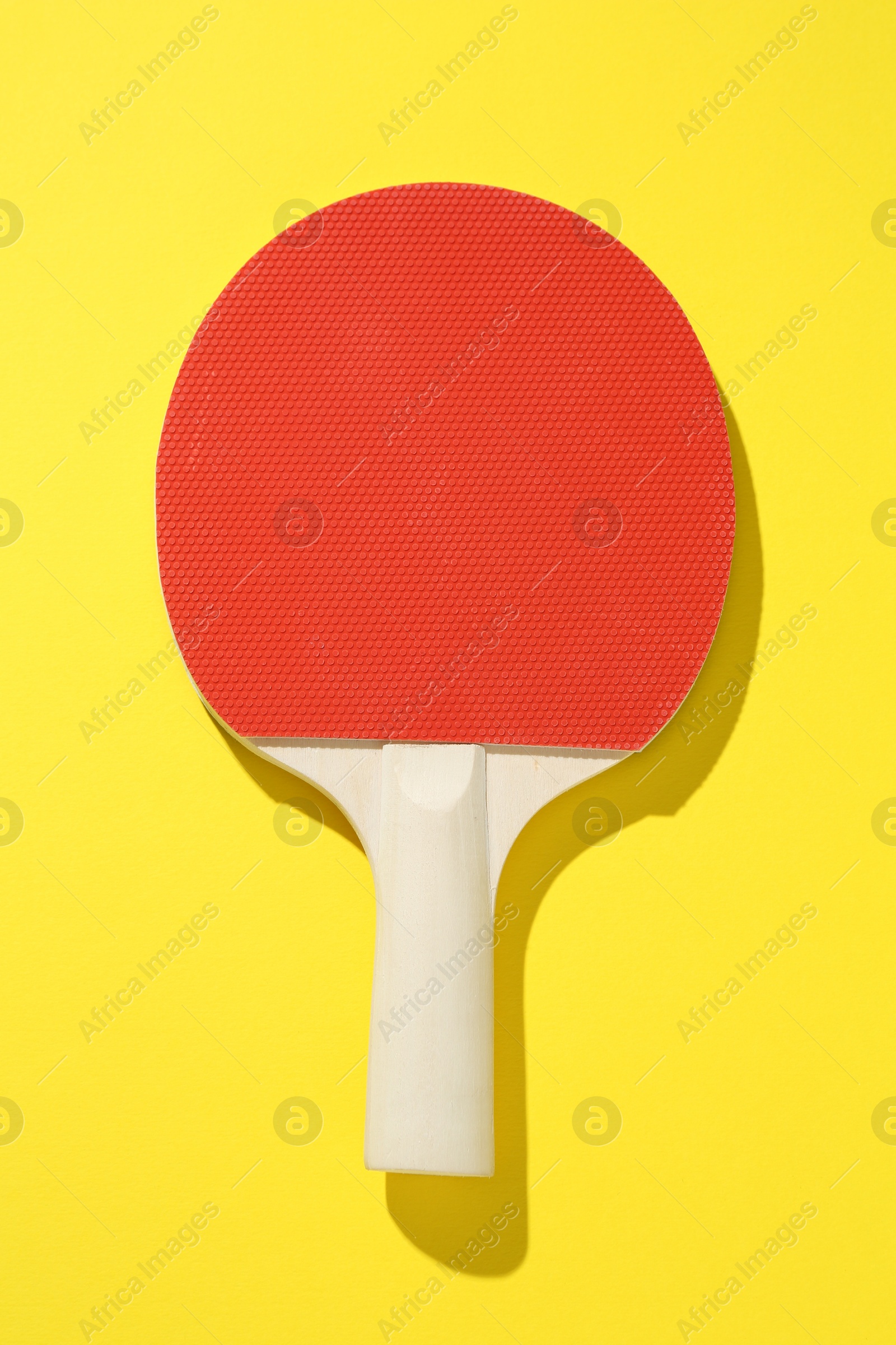 One ping pong racket on yellow background, top view Photo of One ping pong racket on yellow background, top view