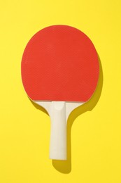 Photo of One ping pong racket on yellow background, top view