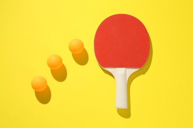 Photo of Ping pong racket and balls on yellow background, flat lay