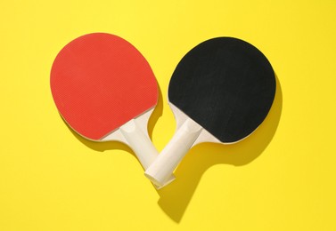 Photo of Ping pong rackets on yellow background, top view