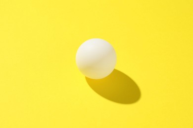 Photo of One ping pong ball on yellow background, closeup