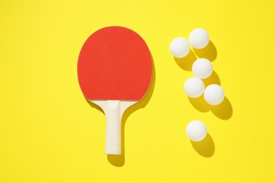 Photo of Ping pong racket and balls on yellow background, flat lay