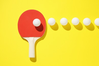 Photo of Ping pong racket and balls on yellow background, flat lay