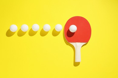 Photo of Ping pong racket and balls on yellow background, flat lay