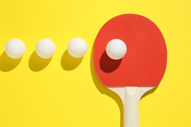 Photo of Ping pong racket and balls on yellow background, flat lay