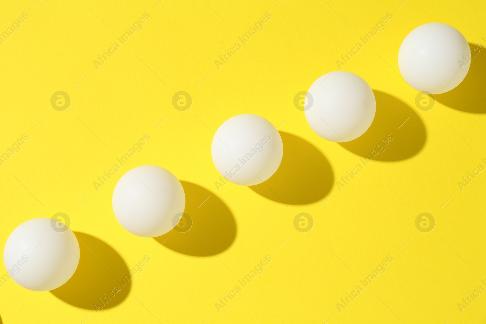 Ping pong balls on yellow background, flat lay Photo of Ping pong balls on yellow background, flat lay