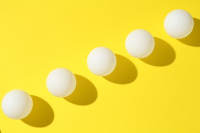 Photo of Ping pong balls on yellow background, flat lay