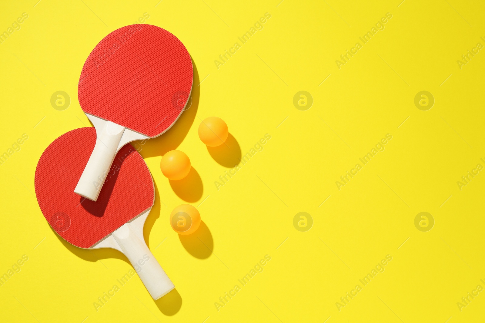 Ping pong rackets and balls on yellow background, flat lay. Space for text Photo of Ping pong rackets and balls on yellow background, flat lay. Space for text