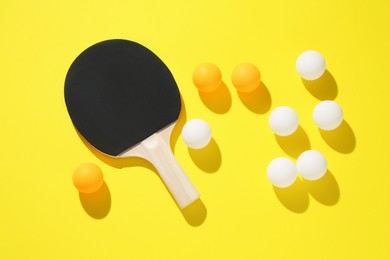 Photo of Ping pong racket and balls on yellow background, flat lay