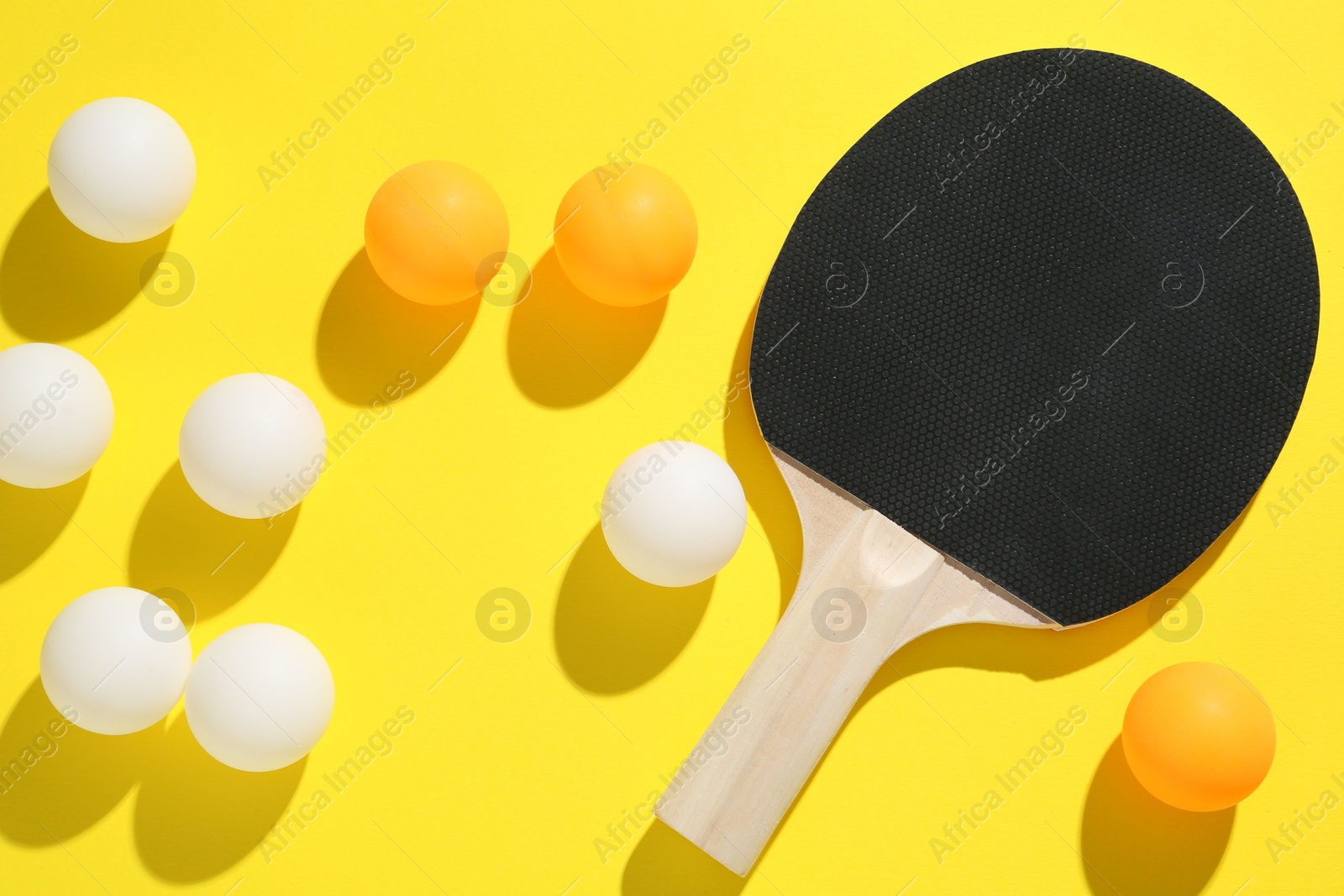 Ping pong racket and balls on yellow background, flat lay Photo of Ping pong racket and balls on yellow background, flat lay