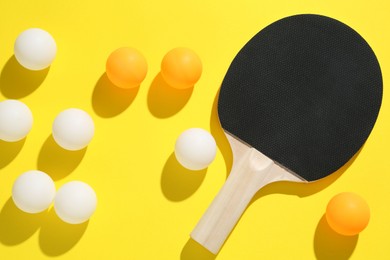 Photo of Ping pong racket and balls on yellow background, flat lay