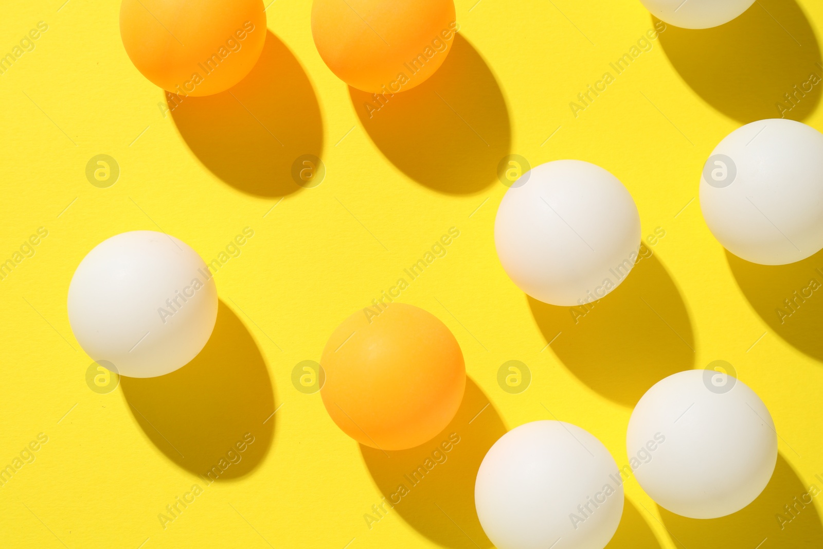 Ping pong balls on yellow background, flat lay Photo of Ping pong balls on yellow background, flat lay