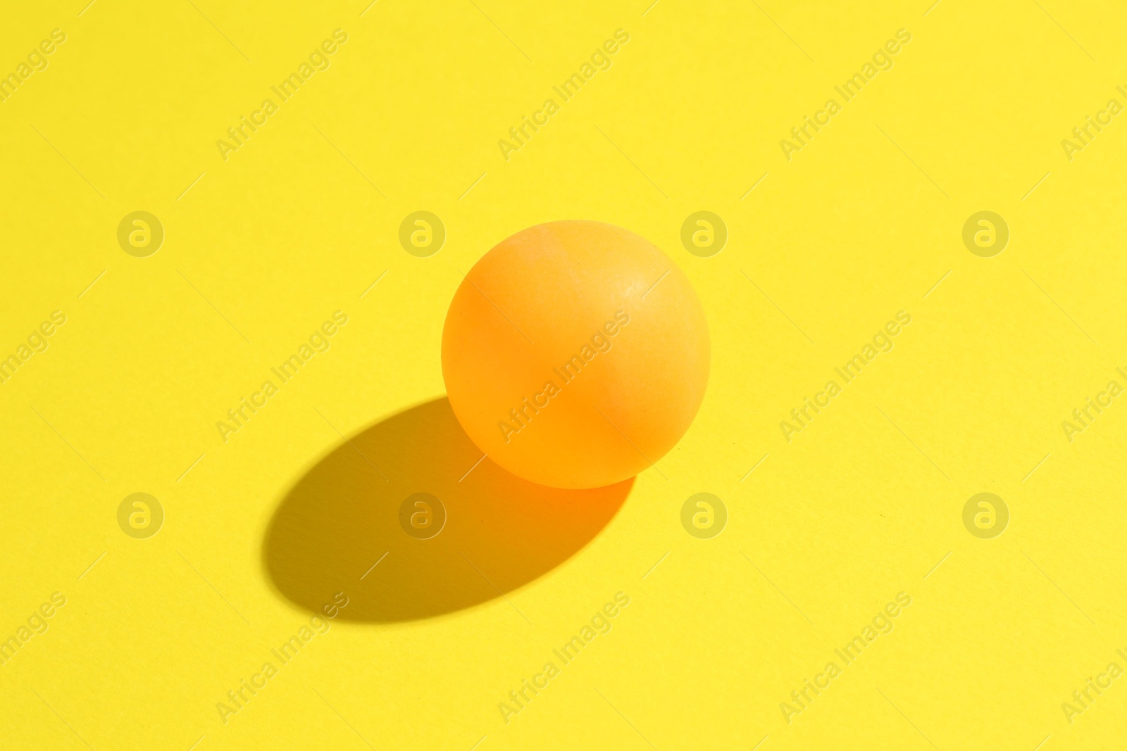 One ping pong ball on yellow background, closeup Photo of One ping pong ball on yellow background, closeup