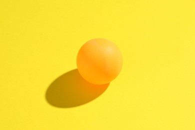 Photo of One ping pong ball on yellow background, closeup
