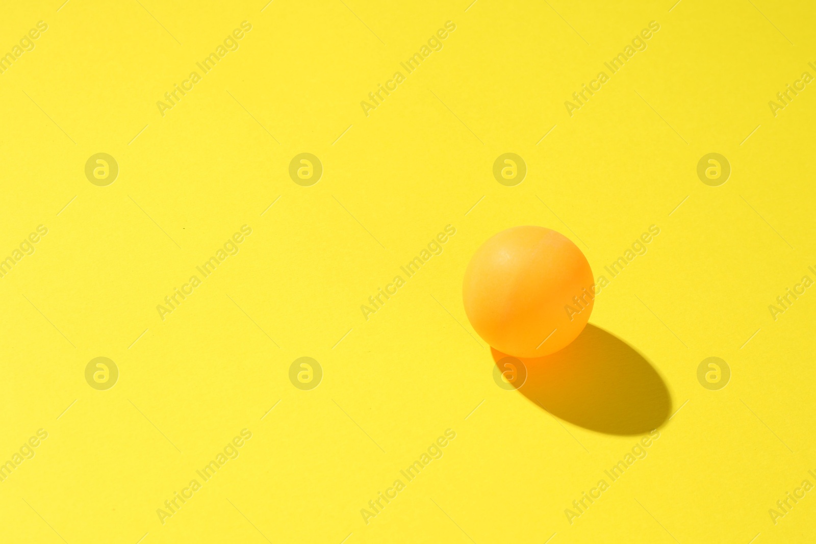One ping pong ball on yellow background. Space for text Photo of One ping pong ball on yellow background. Space for text