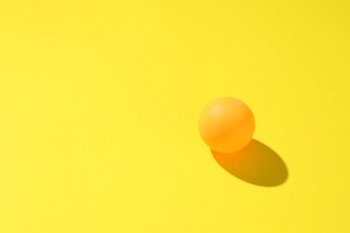Photo of One ping pong ball on yellow background. Space for text