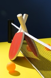 Photo of Ping pong rackets and balls on yellow table