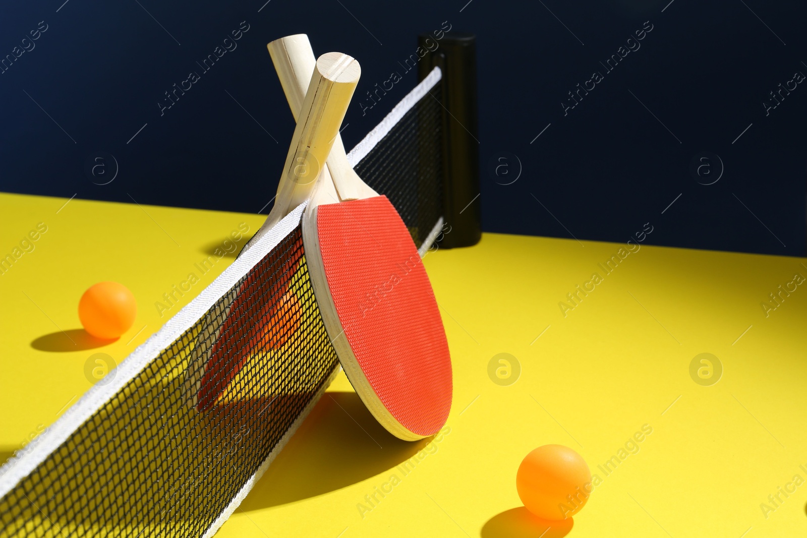 Ping pong rackets and balls on yellow table. Space for text Photo of Ping pong rackets and balls on yellow table. Space for text