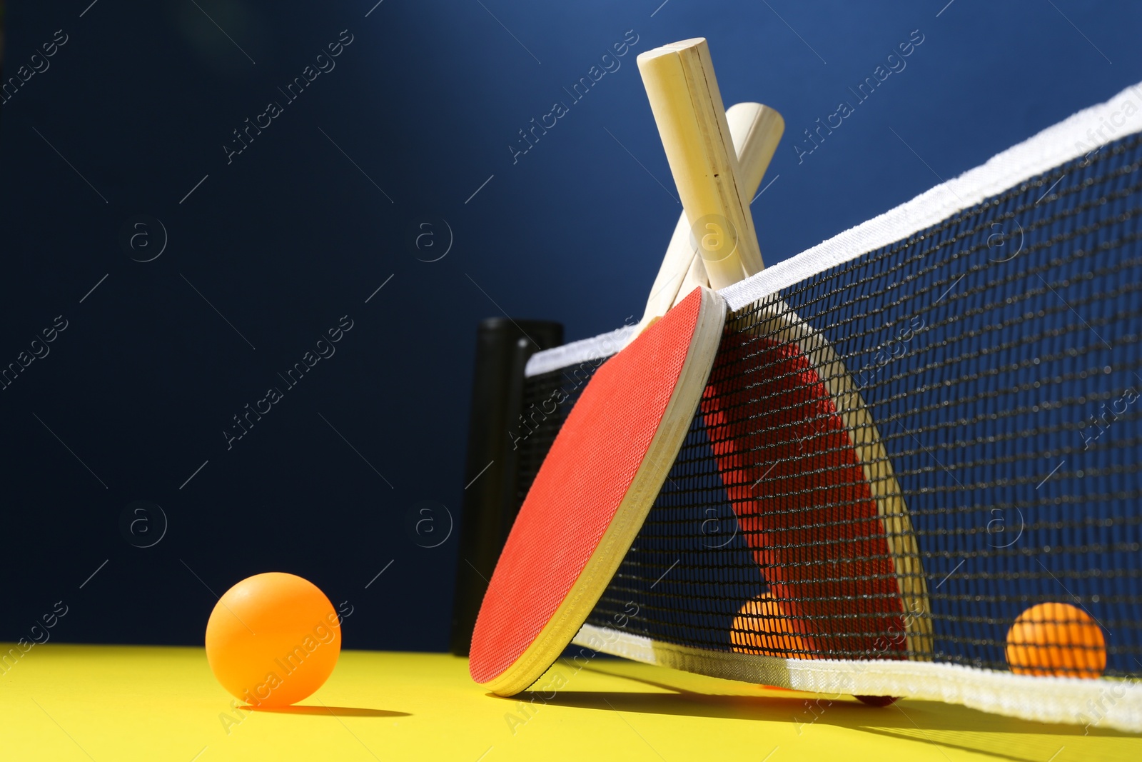 Ping pong rackets and balls on yellow table. Space for text Photo of Ping pong rackets and balls on yellow table. Space for text