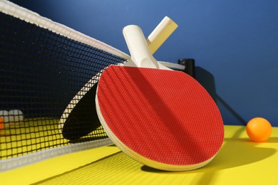 Photo of Ping pong rackets and ball on yellow table