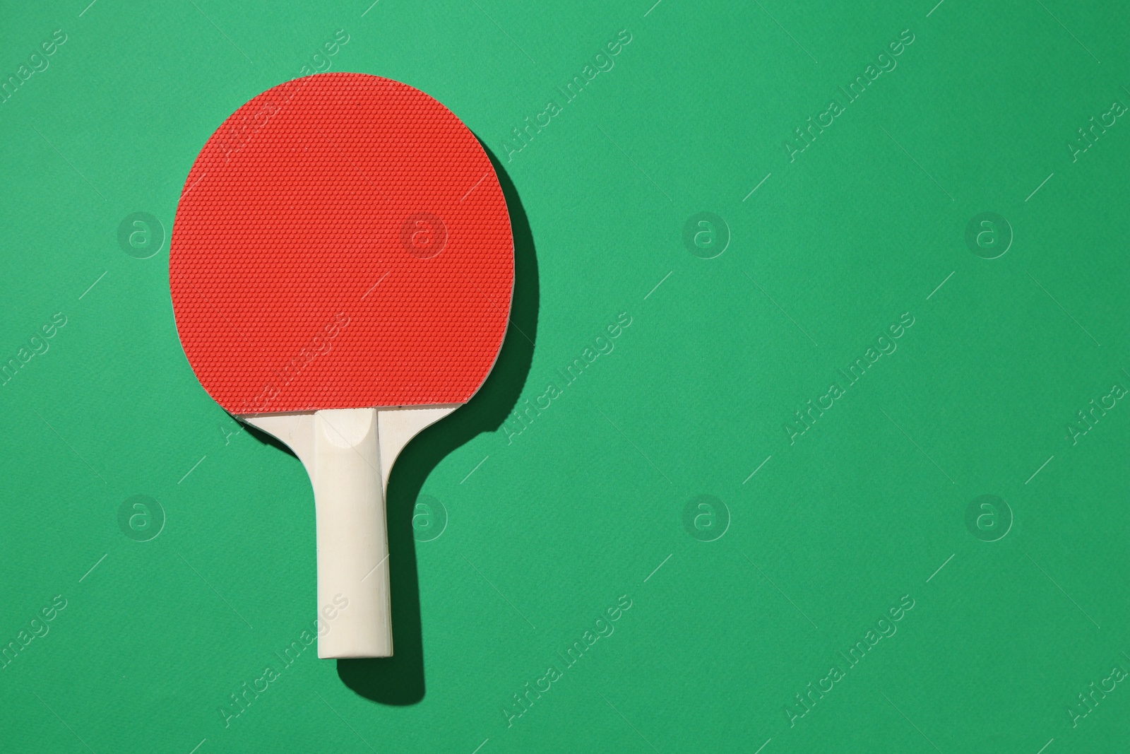 One ping pong racket on green background, top view. Space for text Photo of One ping pong racket on green background, top view. Space for text