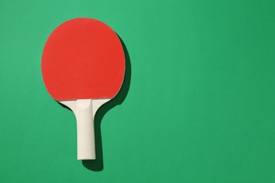 Photo of One ping pong racket on green background, top view. Space for text