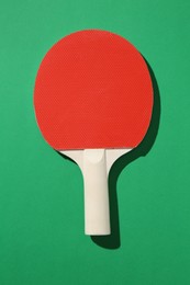 Photo of One ping pong racket on green background, top view