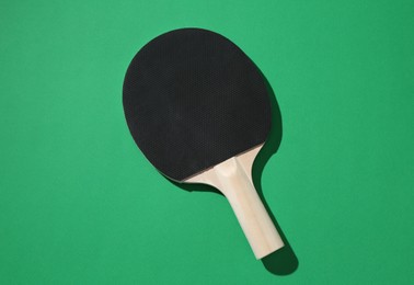 Photo of One ping pong racket on green background, top view