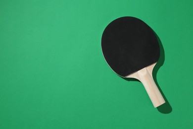 Photo of One ping pong racket on green background, top view. Space for text