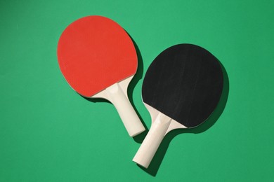Photo of Ping pong rackets on green background, top view