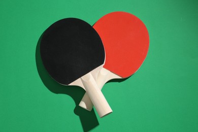 Photo of Ping pong rackets on green background, top view