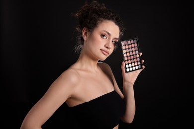 Photo of Woman with eyeshadow palette on black background