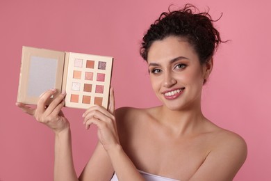 Photo of Smiling woman with eyeshadow palette on pink background