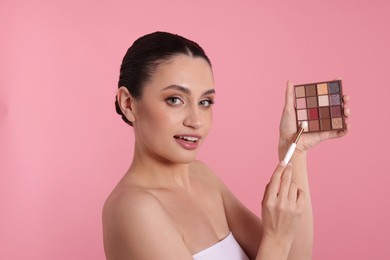 Photo of Woman with eyeshadow palette and brush on pink background