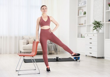 Photo of Beautiful woman exercising with chair at home