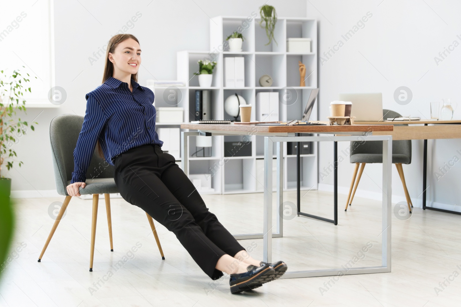 Beautiful woman exercising with chair in office Photo of Beautiful woman exercising with chair in office