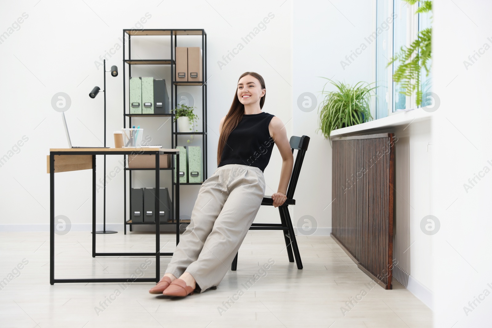 Beautiful woman exercising with chair in office Photo of Beautiful woman exercising with chair in office