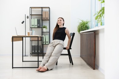 Photo of Beautiful woman exercising with chair in office