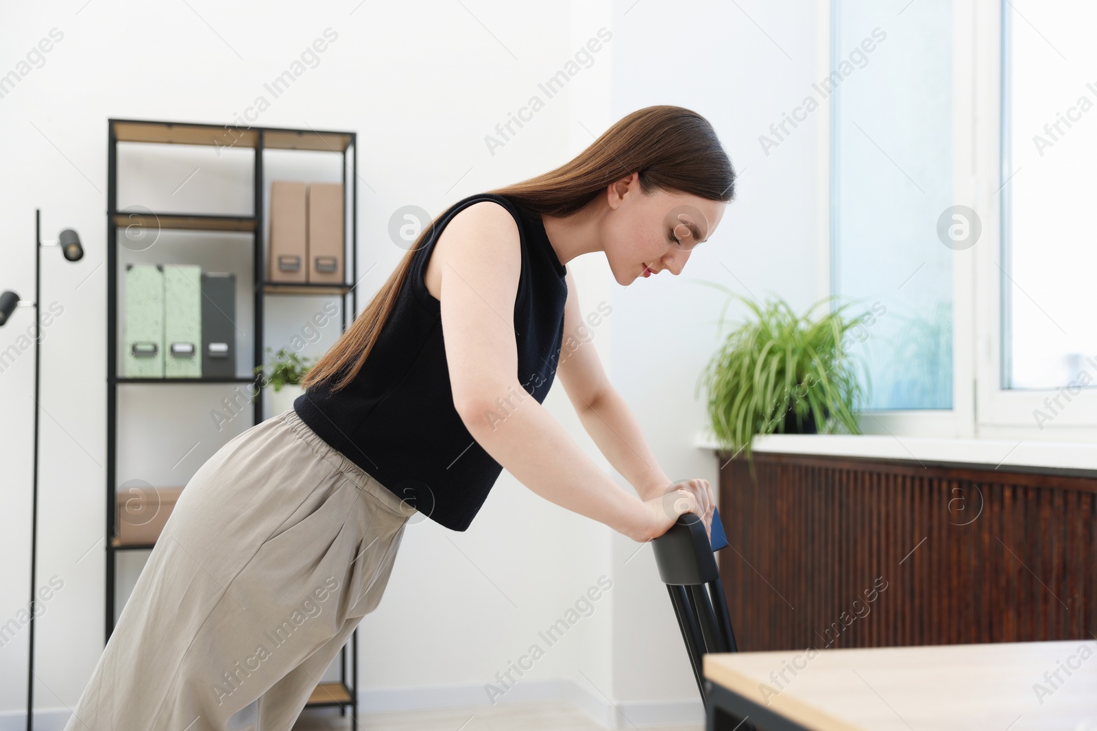 Beautiful woman exercising with chair in office Photo of Beautiful woman exercising with chair in office