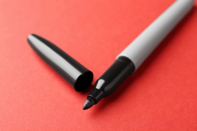 Photo of One black marker on red background, closeup
