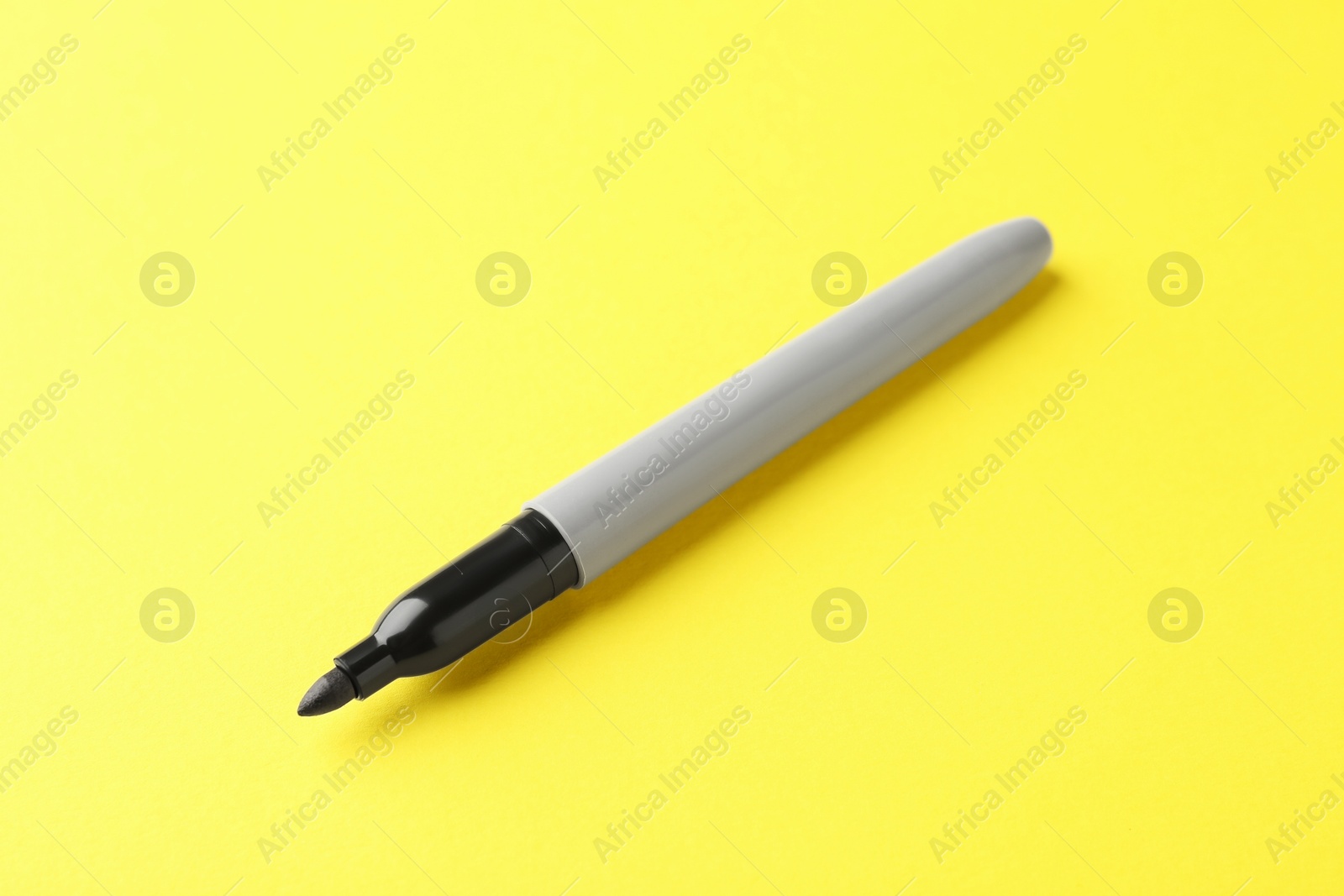 One black marker on yellow background, closeup. Space for text Photo of One black marker on yellow background, closeup. Space for text