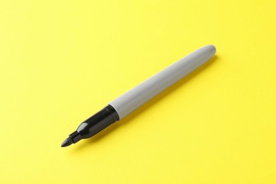 Photo of One black marker on yellow background, closeup. Space for text