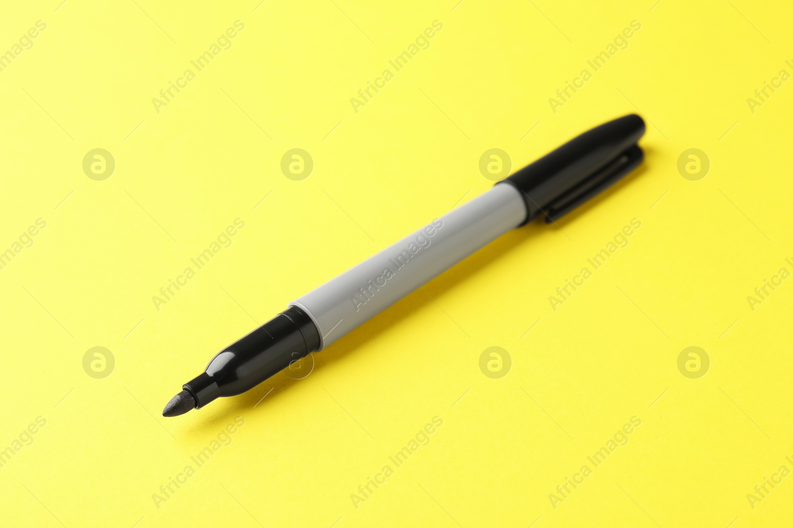One black marker on yellow background, closeup Photo of One black marker on yellow background, closeup