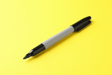 Photo of One black marker on yellow background, closeup