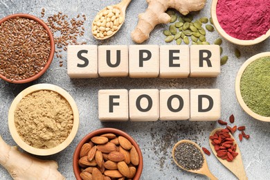 Photo of Wooden cubes with words Super Food, products and supplements on grey textured table, flat lay