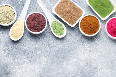 Photo of Different superfood powders on grey textured table, flat lay. Space for text