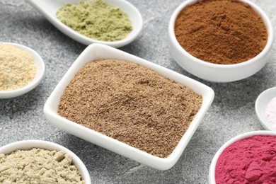 Photo of Different superfood powders on grey textured table, closeup