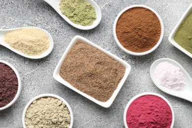 Photo of Different superfood powders on grey textured table, flat lay