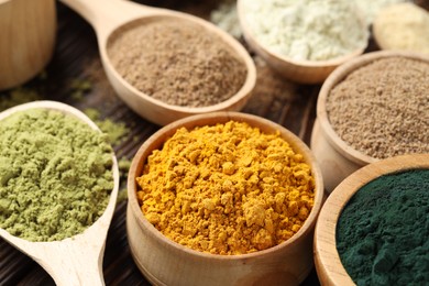 Photo of Different superfood powders on wooden table, closeup